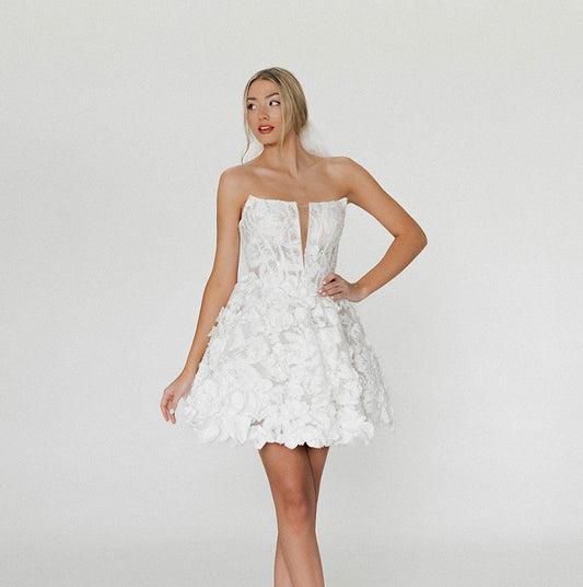 Front view of the Isla Mini showing sculpted 3D floral appliqué and a modern A-line silhouette.